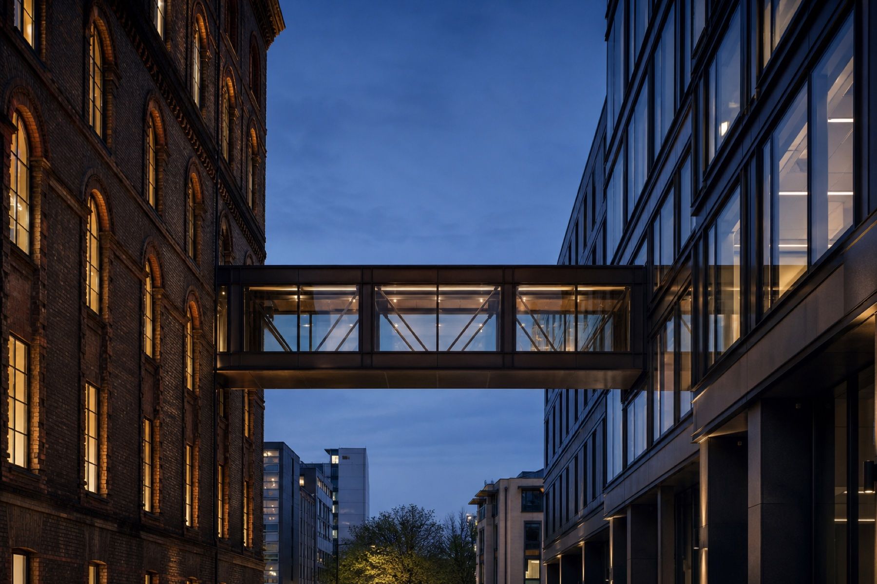 A glazed bridge linking a restored brick warehouse to a modern office building